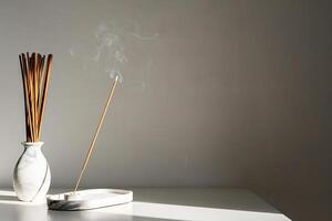 Elegant incense holder with sticks and smoke in minimalist setting. photo