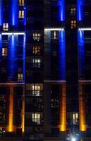 Modern apartment building facade illuminated with vibrant lights at night. Urban living concept photo