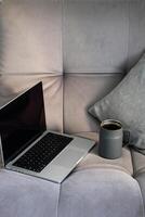 Cozy workspace showing laptop and mug on soft couch. photo