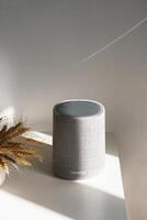 Modern gray speaker on table with soft shadows and light. photo