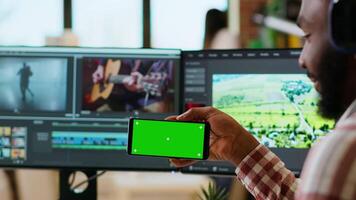 Freelancer male editor works from home with green screen, using dual monitors and tech tools for color grading on a project. Modern remote work and productivity. Camera B video