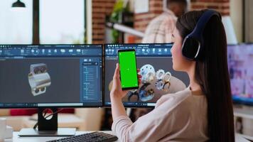 Asian freelancer developer working with headphones and chroma key screen, creating a new prototype for manufacturing industry. Female 3D modeling engineer at her home office. Camera B. video
