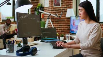 Professional software developer types code on a laptop in a sleek workspace. Asian female freelancer doing remote work on app development, software engineering and agile coding practices. Camera A. video