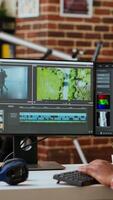 Vertical African american freelancer editing a background at his home office, mixing clips on dual monitors. Professional man employs tech tools for creative and multimedia projects. Camera B. video