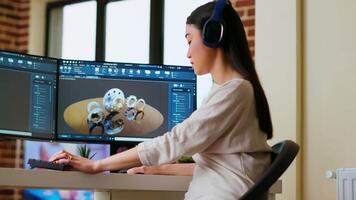 Asian industrial designer puts headset on and works with 3D rendering software, creative freelance tasks. Using dual monitors to enhance multitasking and efficiency for design projects. Camera B. video