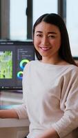 Vertical Asian woman editor working with dual monitors in living room, editing footage and color grading in a modern office setup. Perfect for post production and media creation. Camera B. video