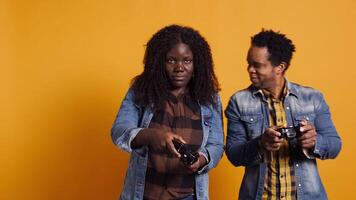 African american life partners playing games together in studio, having fun and enjoying leisure time with their controllers. Cheerful smiling married couple in a competition. Camera B. video