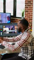 Vertical African american filmmaker man works on a professional shoot, managing the editing timeline of a project. Employing modern editing tools and color grading software. Camera A. video