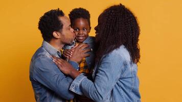 Portrait of african american family with a little child posing on camera, showing gratitude and sympathy towards each other and feeling satisfied. Happy mom and dad holding their boy. Camera A. video