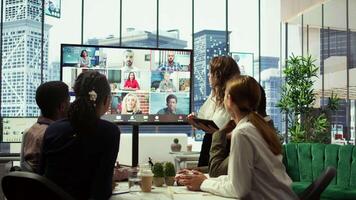 Business team in a boardroom attend videocall meeting with investors group, discussing about increasing funds for a global development plan. Staff and shareholders on teleconference. Camera B. video