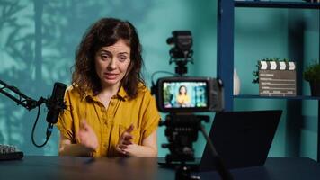 Enthusiastic internet show host hitting the record button on professional camera, using microphone to talk about today topic with subscribers. Media star filming creative vlog, camera A video