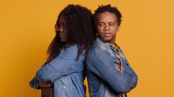 Upset husband and wife dealing with marriage quarrel and conflict, fighting and getting emotional against yellow background. Married irritated couple arguing in disagreement. Camera A. video