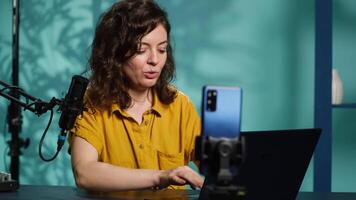 Content creator doing stream, talking to fans about recent news headlines, reading from laptop screen. Woman chatting with subscribers, presenting information on notebook device, camera A video