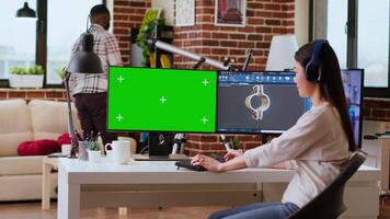 Asian freelancer developer working with headphones and chroma key screen, creating a new prototype for manufacturing industry. Female 3D modeling engineer at her home office. Camera B. video