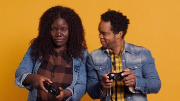 African american life partners playing games together in studio, having fun and enjoying leisure time with their controllers. Cheerful smiling married couple in a competition. Camera A. video