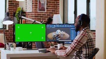 African american industrial designer works on 3D renders and isolated mockup, using digital tools and dual monitors. Engineer driven by creativity and technical expertise in design. Camera B. video