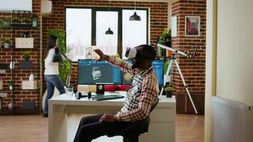 African american software developer working with virtual reality headset and artificial intelligence to create new industrial prototypes and manufacturing tools on CAD software. Camera A. video