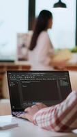 Vertical African american software engineer works on a laptop typing code for a development project. Technical specialist multitasking, debugging and using advanced digital tools for coding. Camera B. video