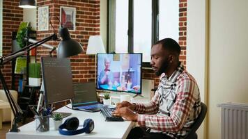 Male coder works from home typing code on a laptop in a modern living room. African american IT engineer using programming language and cloud computing for software development. Camera A. video
