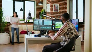 African american man editor working in production industry, does color grading and editing a film project on dual monitors. Showing the creative process with tech tools. Camera A. video
