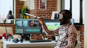 African american editor uses virtual reality glasses to do color grading, working with high tech vr headset and dual monitors at his home office. Filmmaker editing clips. Camera B. video