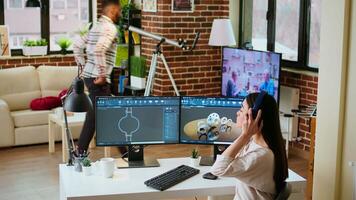 Asian professional engineer works on coding industrial designs using advanced software tools. Living room office includes dual monitors and technical equipment for high productivity. Camera A. video