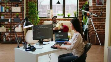 Asian female developer coding cloud computing applications on pc in a modern tech workspace. Woman IT specialist focuses on the software development process for productivity and innovation. Camera A. video