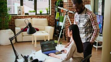 Diverse software developers team coding on a laptop in a cozy home office, working on a new program or app development. Specialists in IT promote programming language and remote tech work. Camera A. video