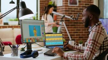 African american photo editor retouches images on his computer in a tech inspired workspace. Man does freelance tasks for photo retouching and digital art, media and graphic design sectors. Camera B. video