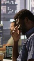 Vertical System administrator in office yawning during shift, feeling tired while looking at software interface on PC. Exhausted man being sleepy in workspace, programming on computer monitor, camera A video