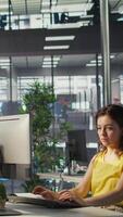 Vertical Worker sitting at office desk using computer during job shift, looking through online financial business documents. Company employee in workspace doing tasks on PC, being productive, camera B video