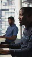 Vertical Admin creating AI machine learning models that can process and analyze data to improve decision making processes, looking at PC. Man programming in office using artificial intelligence tech, camera B video