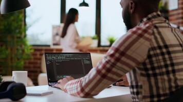 africano americano Programas engenheiro trabalho em uma computador portátil digitando código para uma desenvolvimento projeto. técnico especialista multitarefa, depuração e usando avançado digital Ferramentas para codificação. Câmera b. video