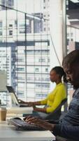 Vertical Happy coworker in wheelchair bumping fists with programmer testing machine learning technology. Person with disability saluting colleague in inclusive office, doing friendly gesture, camera B video