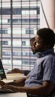 Vertical Tired admin stretches limbs while using PC for artificial intelligence computing simulating human brain. Fatigued worker relaxing back, feeling strained after working with AI neural networks, camera A video
