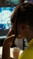 Vertical Staff member in office yawning during shift, feeling tired while looking at artificial intelligence software on PC. Exhausted african american AI company employee being sleepy in workspace, camera A video