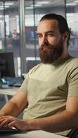 Vertical Meticulous staff member imputing data on computer in office. Adept worker at desk focused on typing company statistical numbers, working hard to finish job before deadline, camera B video