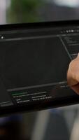 Vertical Data scientist uses tablet to check on machine learning models that can analyze data to automate decision making processes. Close up of IT specialist using device to do programming in office, camera A video