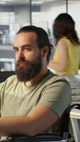 Vertical System administrator with disability in inclusive workspace training machine learning models. IT specialist with paraplegia monitoring and maintaining company systems, camera B video