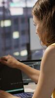Vertical Woman in office using laptop to steal company secrets after being hired by competitor, hiding from manager. Sneaky employee closing notebook lid to hide while ilegally downloading data, camera A video