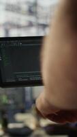 Vertical Data scientist uses tablet to check on machine learning models that can analyze data to automate decision making processes. Close up of IT specialist using device to do programming in office, camera B video