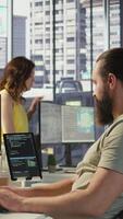 Vertical Employee utilizing AI resources and platforms to train and deploy machine learning models, handheld camera shot. Man monitoring and maintaining artificial intelligence company systems, camera B video