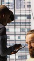 Vertical Technician and colleague using device for managing cloud computing platforms training machine learning models. IT staff members in office monitoring company systems using tablet, camera A video