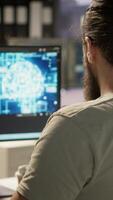 Vertical Software technician using computer for artificial intelligence computing simulating human brain. Close up of employee working with AI deep neural networks on desktop PC, camera A video
