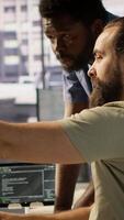 Vertical Manager correcting programmer mistakes while conducting code review to fix errors, identifying technical issues with company software. Team leader supervising IT staff member optimizing code, camera A video