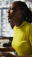 Vertical Tired african american programmer having strained eyesight from overworking in office. Close up of woman at work removing eyeglasses to rub eyes, looking at PC screen for too long, camera B video