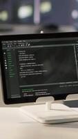 Vertical Programming language on digital device screen in empty IT department office used for app development. Close up of tablet left open on desk in tech startup company workspace with nobody in video