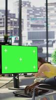 Vertical Person with disability testing and deploying programs and systems on green screen PC. Software technician in wheelchair checking code on mockup PC, sitting at desk in office, camera B video