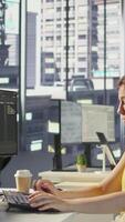 Vertical Manager in wheelchair passing by desk of employee testing machine learning company software to minimize occurrence of bugs. Woman works in inclusive workspace with workers with disabilities, camera B video