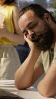 Vertical Tired company worker caught falling asleep at desk in office by colleague, laughing about it. Exhausted man sleeping in front of computer screen in workplace, woken up by amused coworker, camera A video